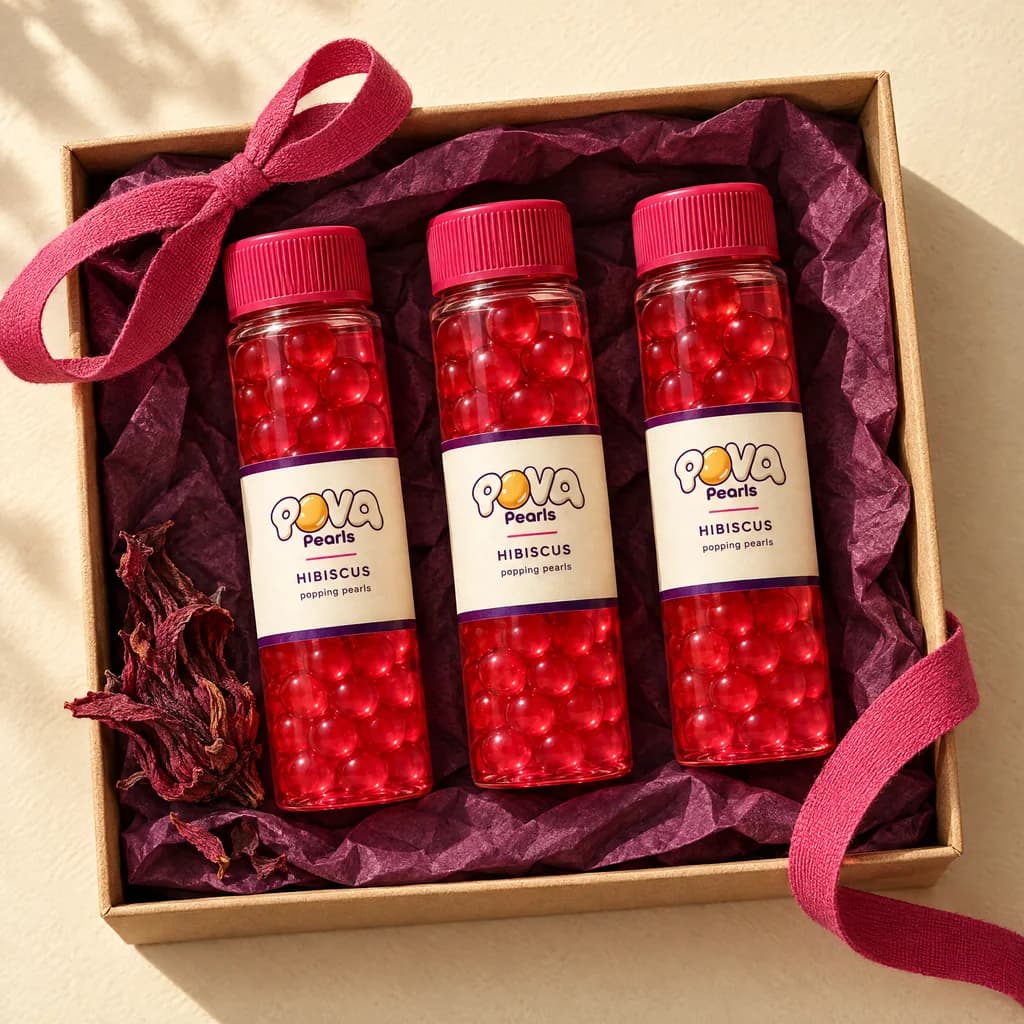 Three vials resting on plum tissue in a plain open tray with a pink ribbon and a dried hibiscus flower